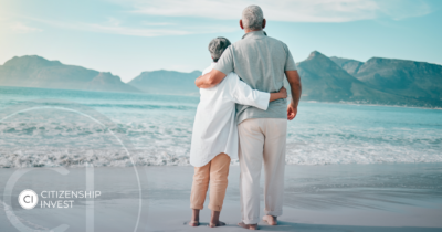 Senior couple embracing while looking at the ocean on a tropical beach, symbolizing peaceful retirement in the Caribbean