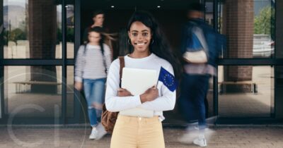 A young African student smiles confidently outside a European university, symbolizing access to education through international programs.